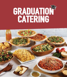 A display of an assortment of foods for graduation catering from Sauce Pizza and Wine, including pizza, salads, pasta, and macaroni and cheese.