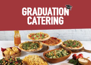 A display of an assortment of foods for graduation catering from Sauce Pizza and Wine, including pizza, salads, pasta, and macaroni and cheese.